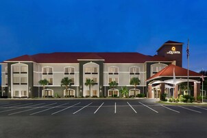 Un hotel con techo rojo, varios pisos y estacionamiento.