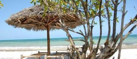 Praia particular, areia branca, espreguiçadeiras, guarda-sóis