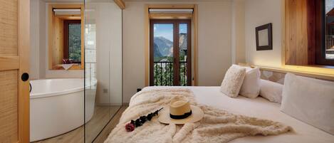 Un dormitorio con una cama, una ventana con vistas a la montaña, una bañera y un techo de madera.