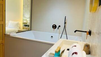 Ein modernes Badezimmer mit einer großen Badewanne, einem Spiegel und einem Handtuchhalter.