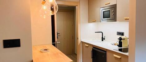 Una cocina compacta con una mesa de madera, un microondas y un lavavajillas.