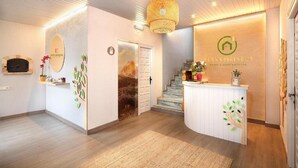 Een hotel receptie met een houten receptiebalie, een trap en een bordje aan de muur.
