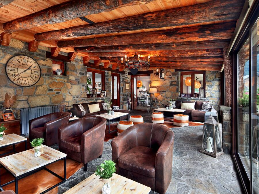 Un interior rústico con paredes de piedra, muebles de cuero y un gran reloj.