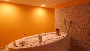 A modern bathroom with an oval bathtub, a mosaic wall, and a ceiling with recessed lighting. - Hotel Princess (Bar)