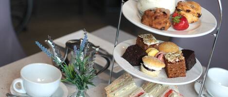 A tiered dessert stand with various pastries and sandwiches.