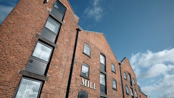 Un edificio de ladrillo con la palabra "MILL" en la fachada, varias ventanas y un cielo despejado al fondo.