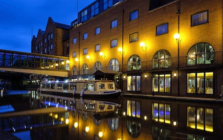 A canal-side building with multiple windows and a boat docked in front.