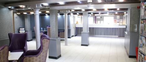 A spacious indoor area with seating arrangements and a counter, likely a lobby or waiting area.