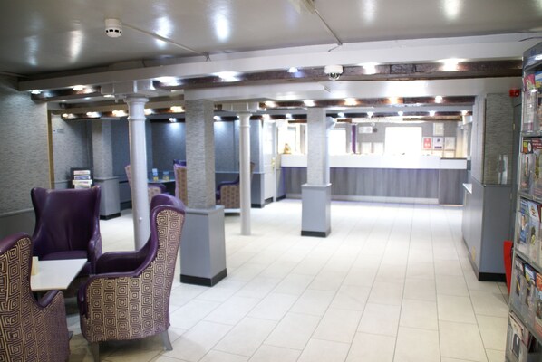 A spacious indoor area with seating arrangements and a counter, likely a lobby or waiting area.