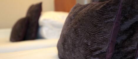 A bed with white linens and dark brown pillows.