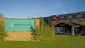 Indicador de Rochester Calafate, un edifici modern amb façana de pedra i detalls de fusta, envoltat de vegetació.