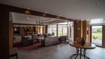 A spacious lobby with a seating area, a dining table, and a large window offering a view of the outdoors.