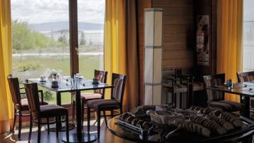 A restaurant with tables and chairs, a buffet with pastries, and a view of the outdoors.