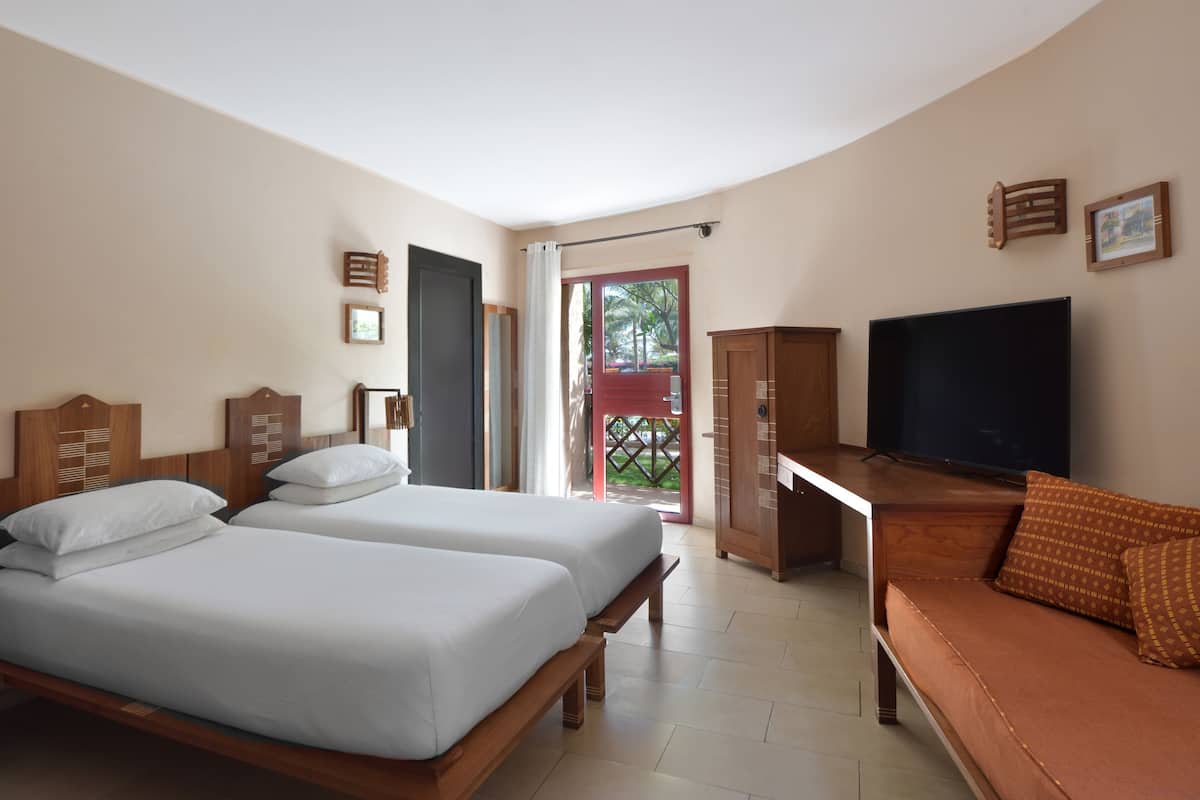 Quarto de hotel com duas camas, televisão, escrivaninha e sofá.