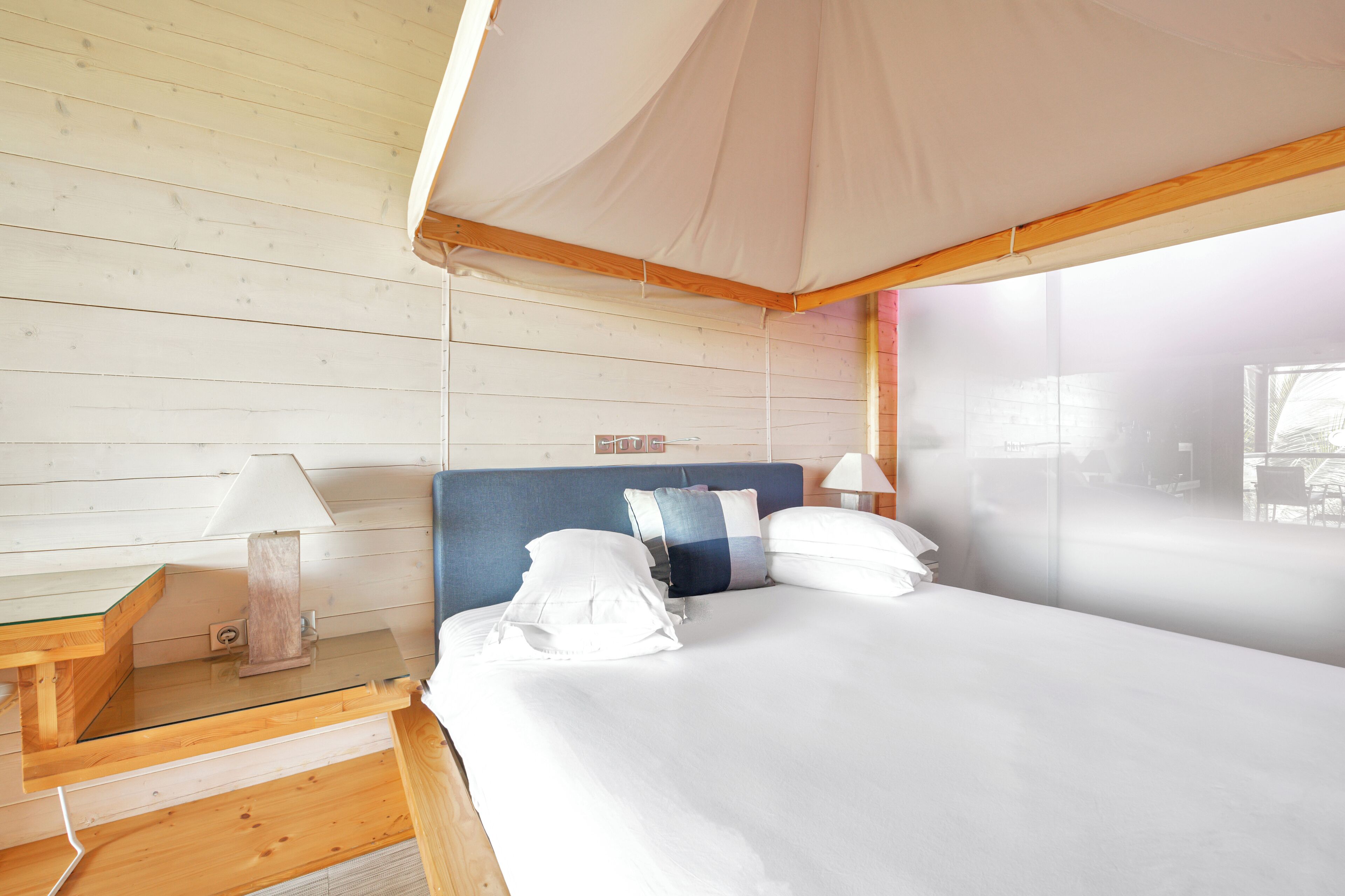 A bedroom with a canopy bed, wooden walls, and a view of the outside.