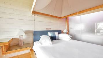 A bedroom with a canopy bed, wooden walls, and a view of the outside.