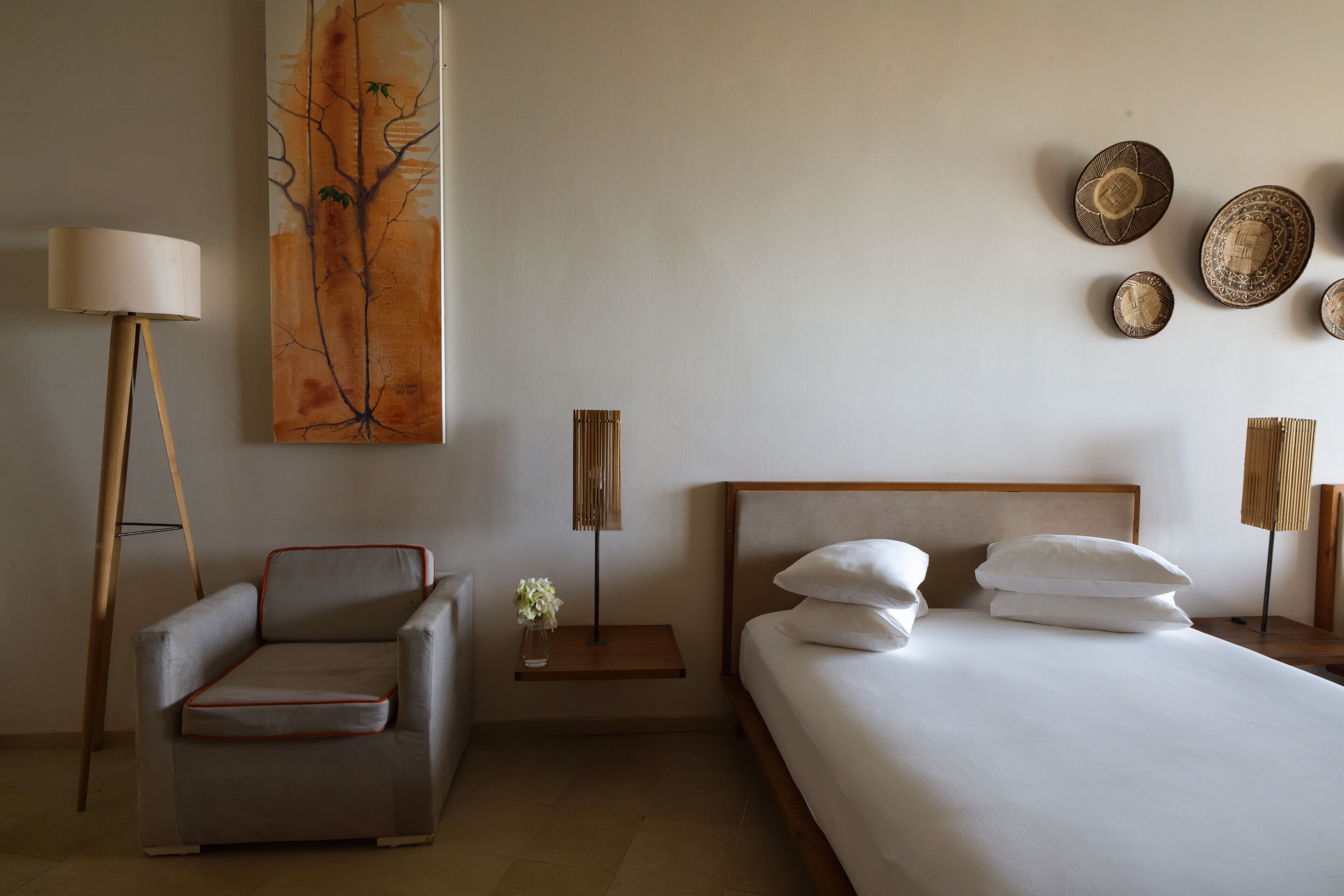 Una habitación de hotel moderna con una cama, un sofá, una mesita de noche, una lámpara y obras de arte en la pared.
