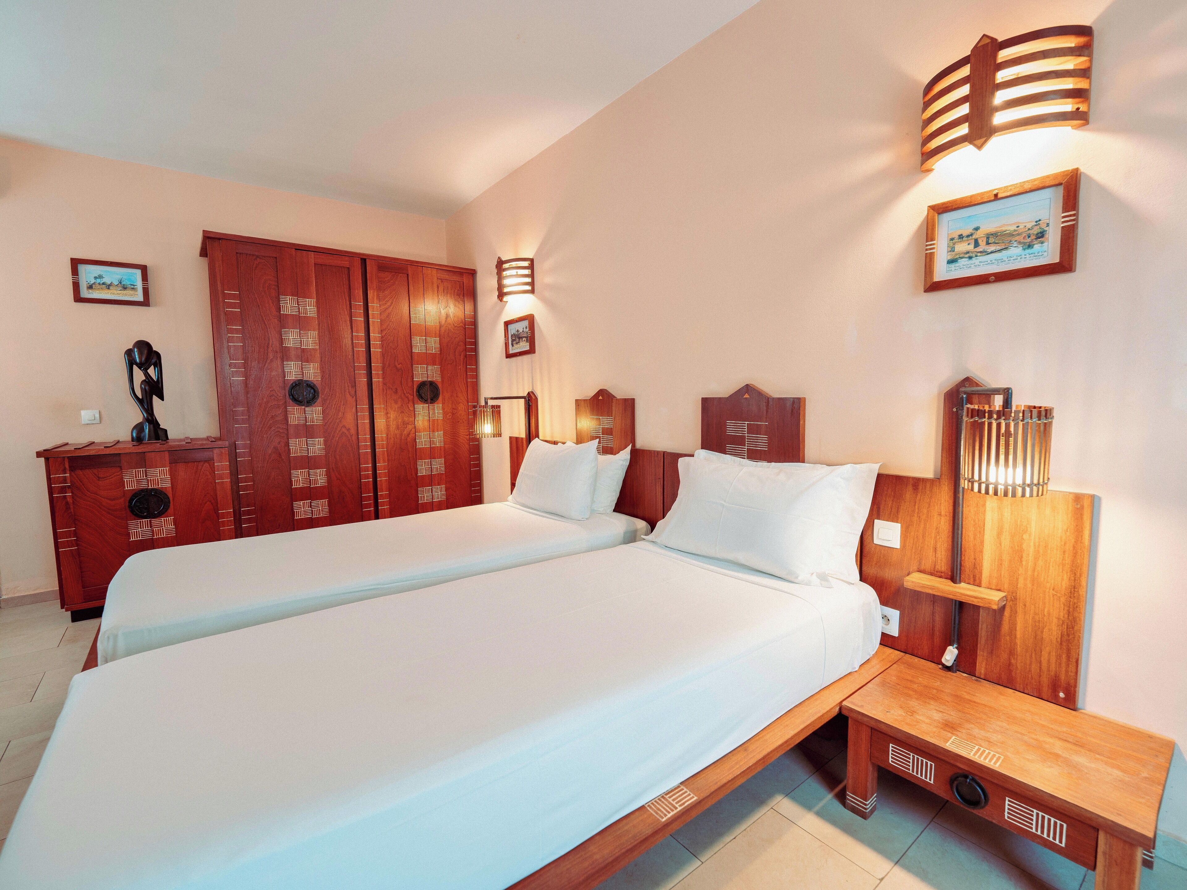 Habitació d'hotel amb un llit gran, armari de fusta i il·luminació penjada a la paret.