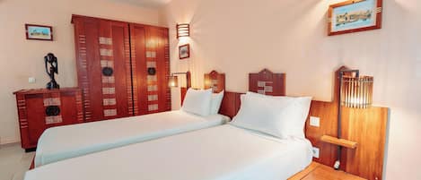 Habitación de hotel con una cama grande, armario de madera e iluminación montada en la pared.