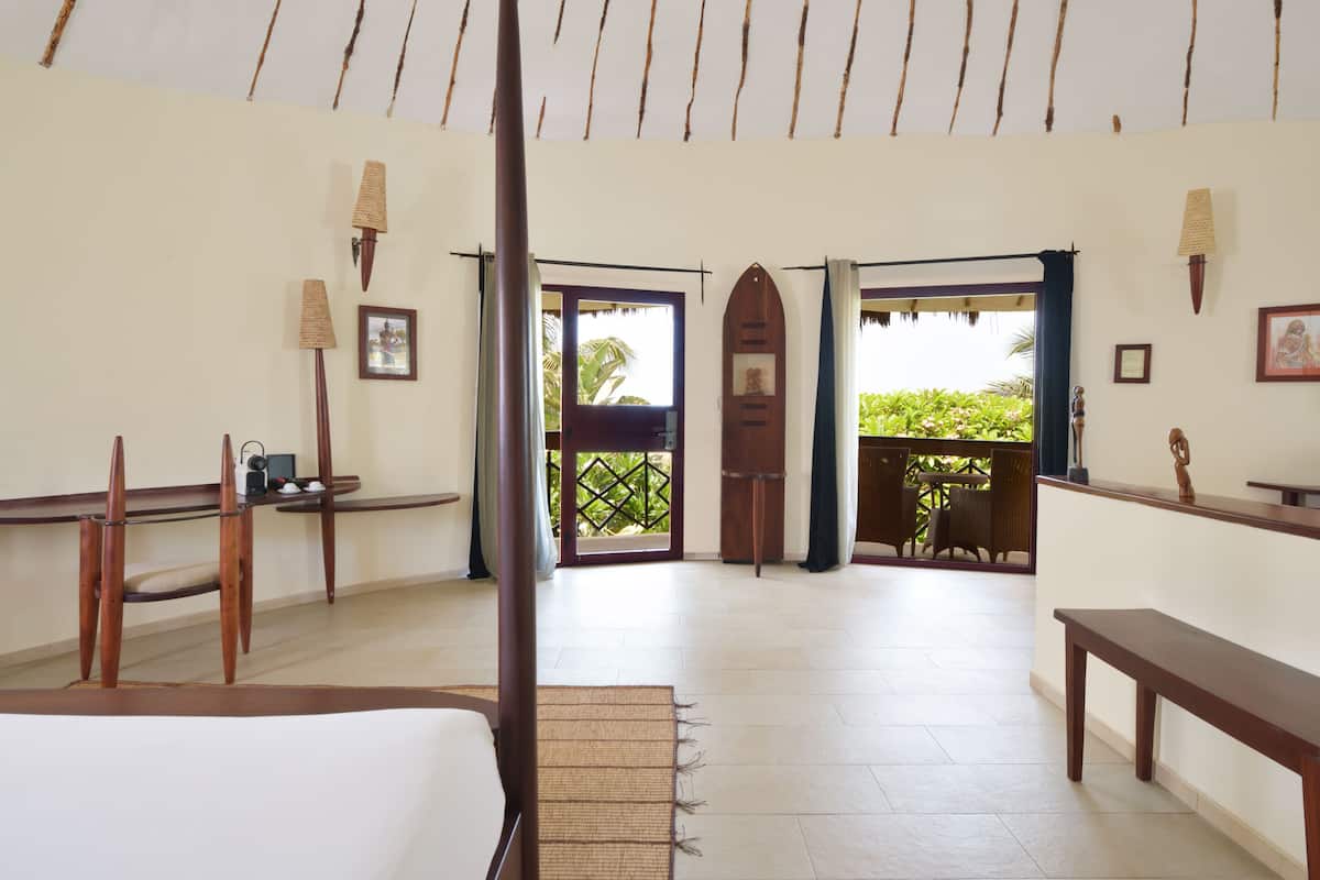 Um quarto com cama, escrivaninha, cadeira, janela e varanda.
