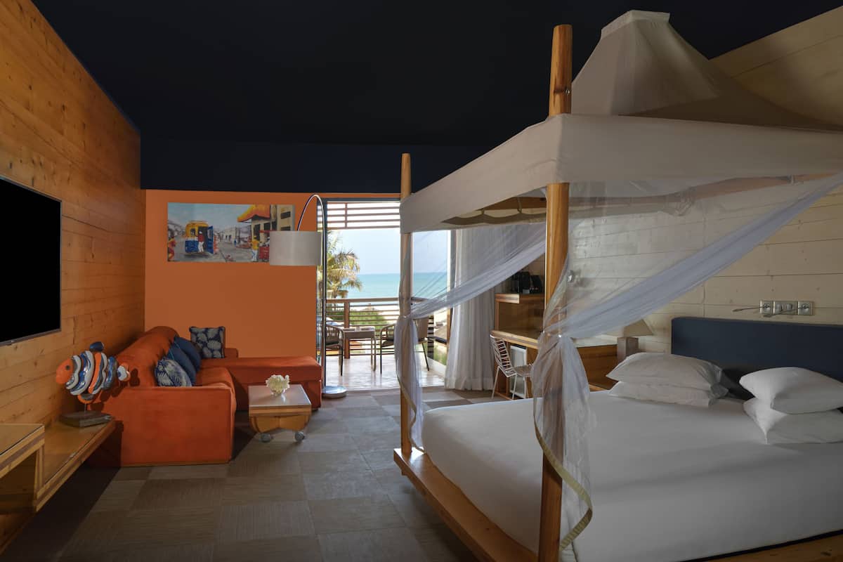 Quarto com cama, sofá, televisão e um quadro retratando uma cena de rua.