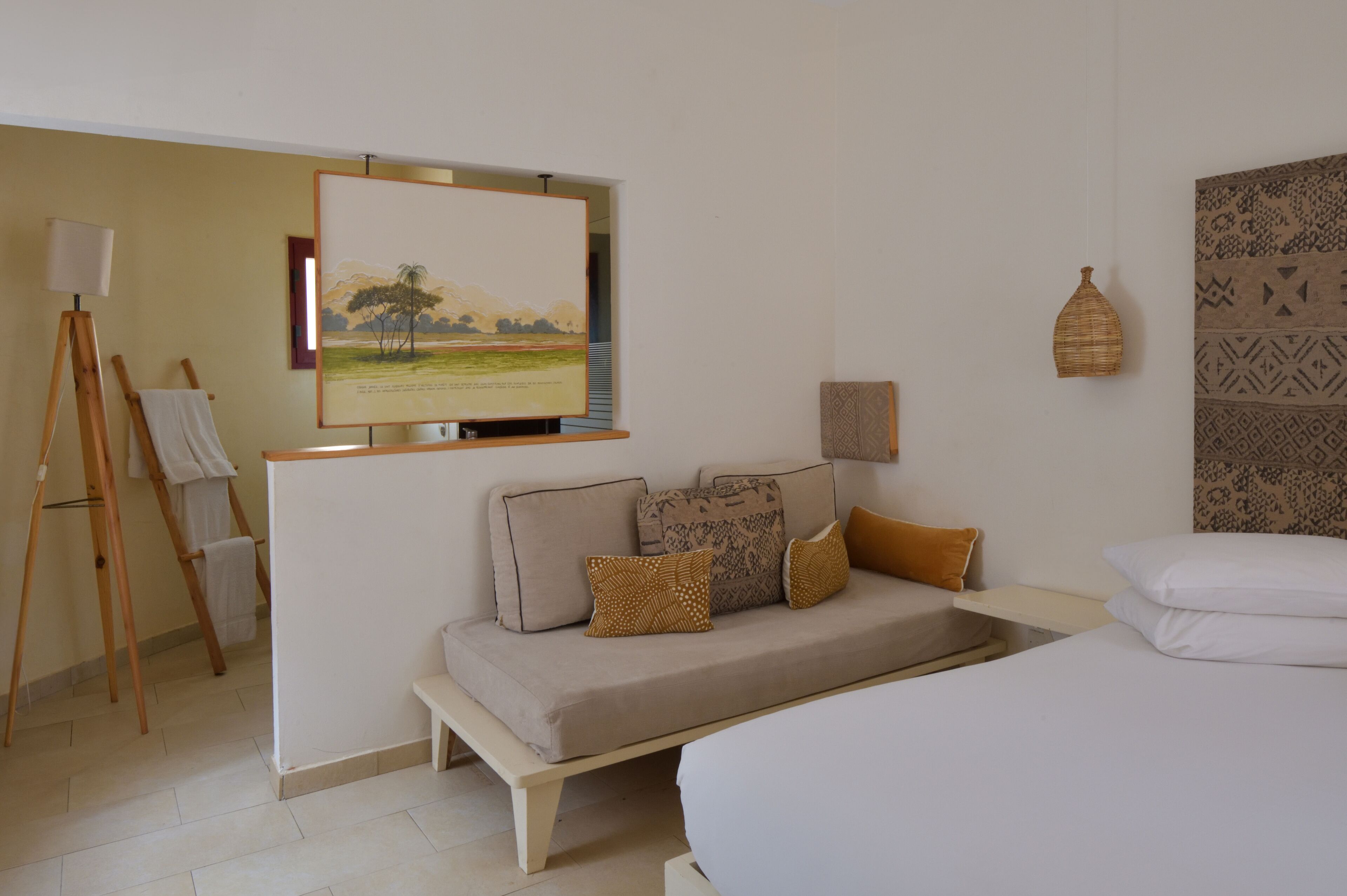 Een hotelkamer met een bed, een bank, een schilderij aan de muur en een lamp.