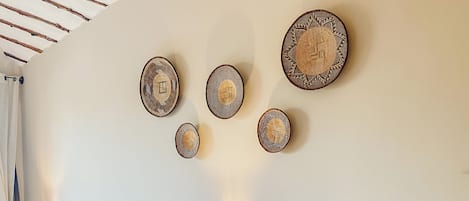 Habitación de hotel con dos camas, techo de vigas de madera y platos decorativos colgados en la pared.