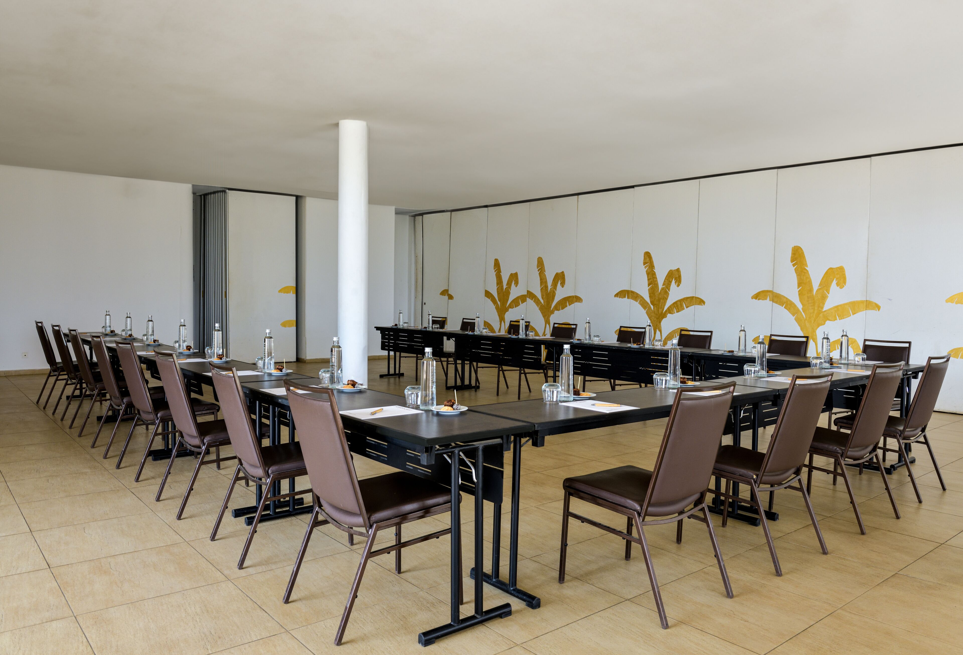 A conference room with long tables, chairs, and water bottles.