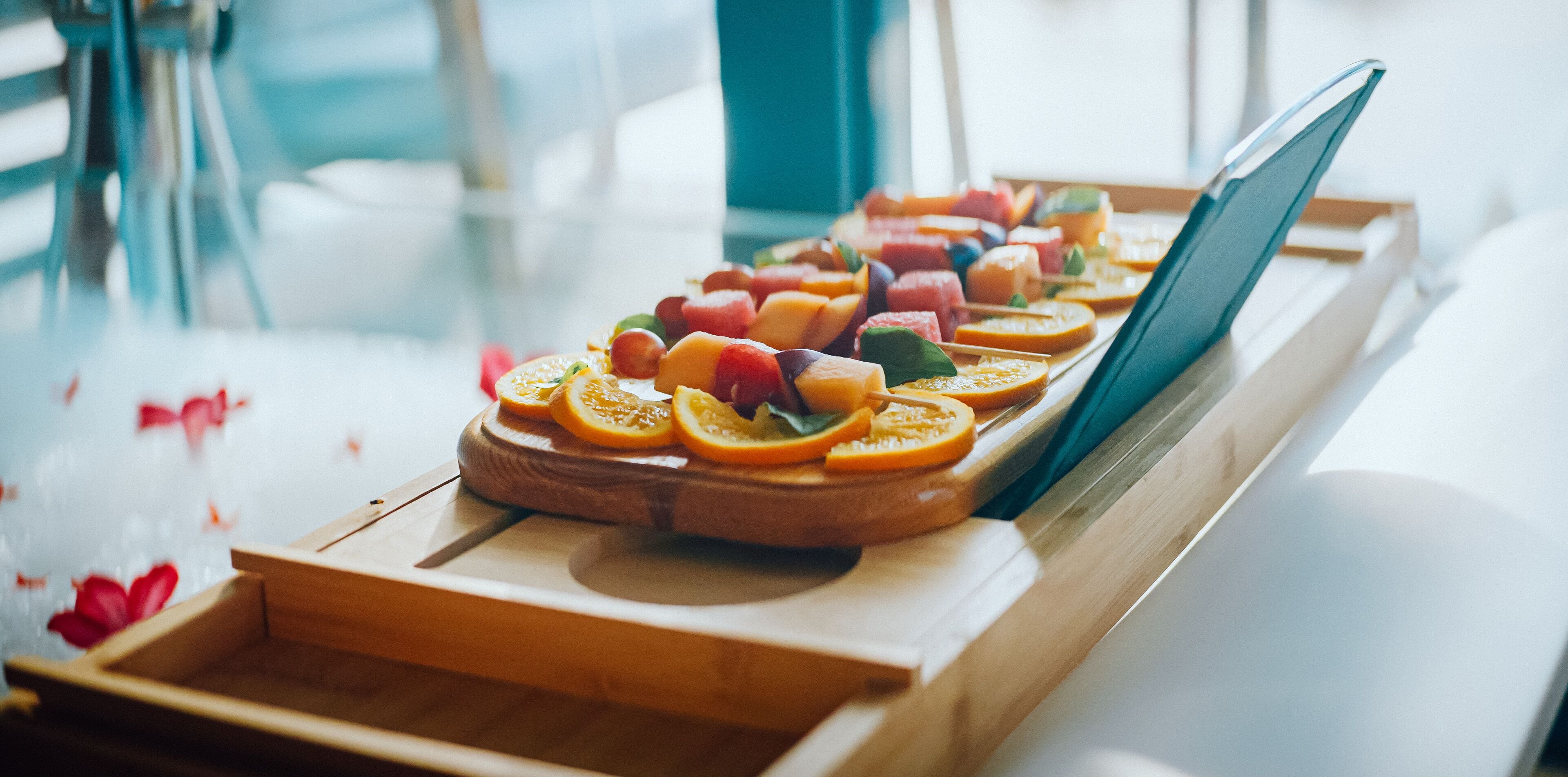 A wooden tray with fruit skewers on a table.