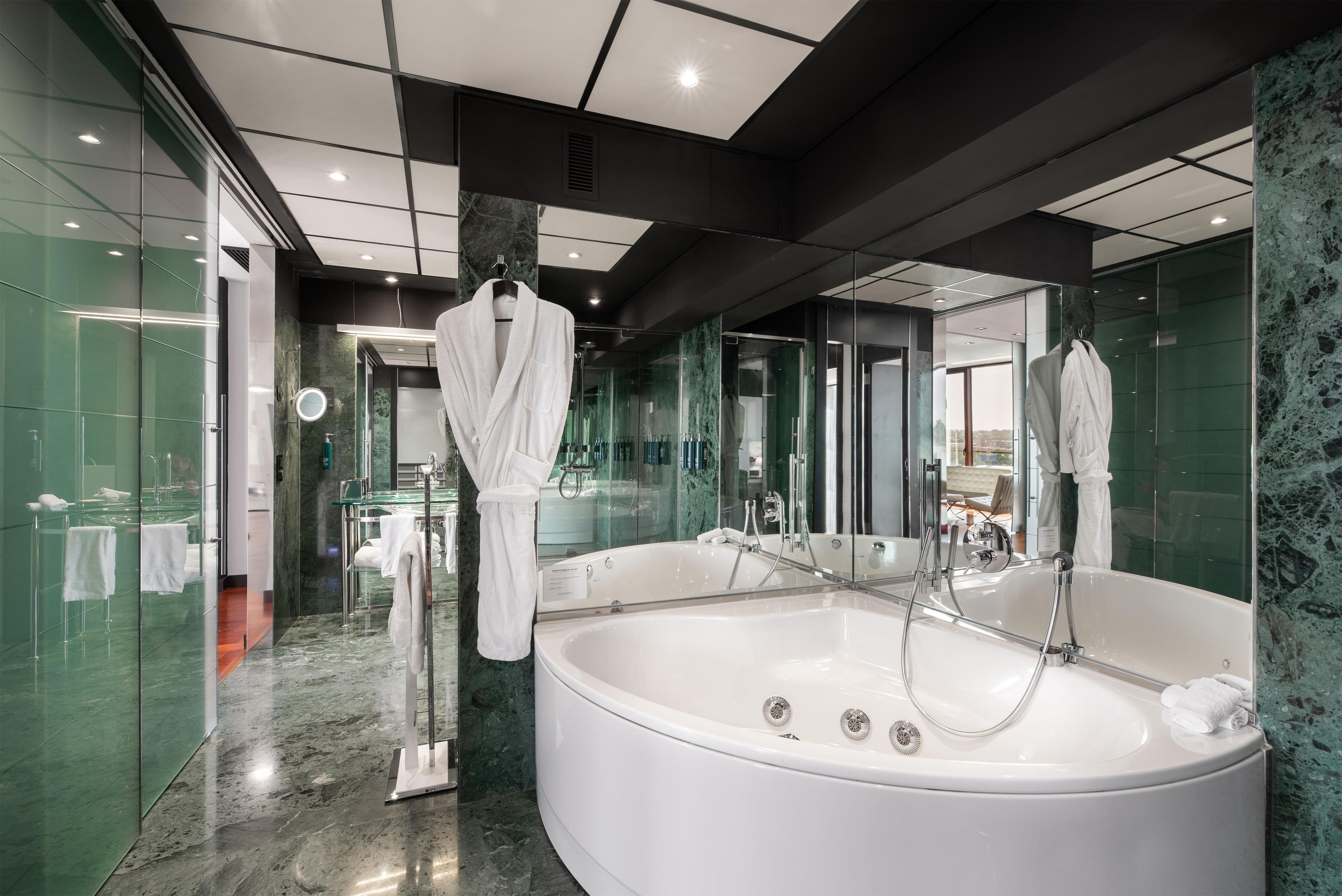 Un bagno moderno con una grande vasca da bagno, box doccia in vetro e pareti in marmo.