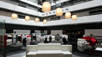A modern hotel lobby with a reflective floor, multiple levels of balconies, and contemporary lighting fixtures.