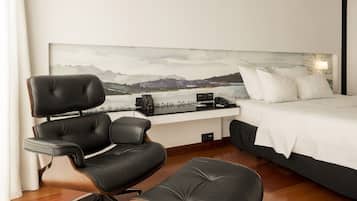 Una habitación de hotel moderna con una cama grande, un escritorio con silla y un cuadro en la pared.