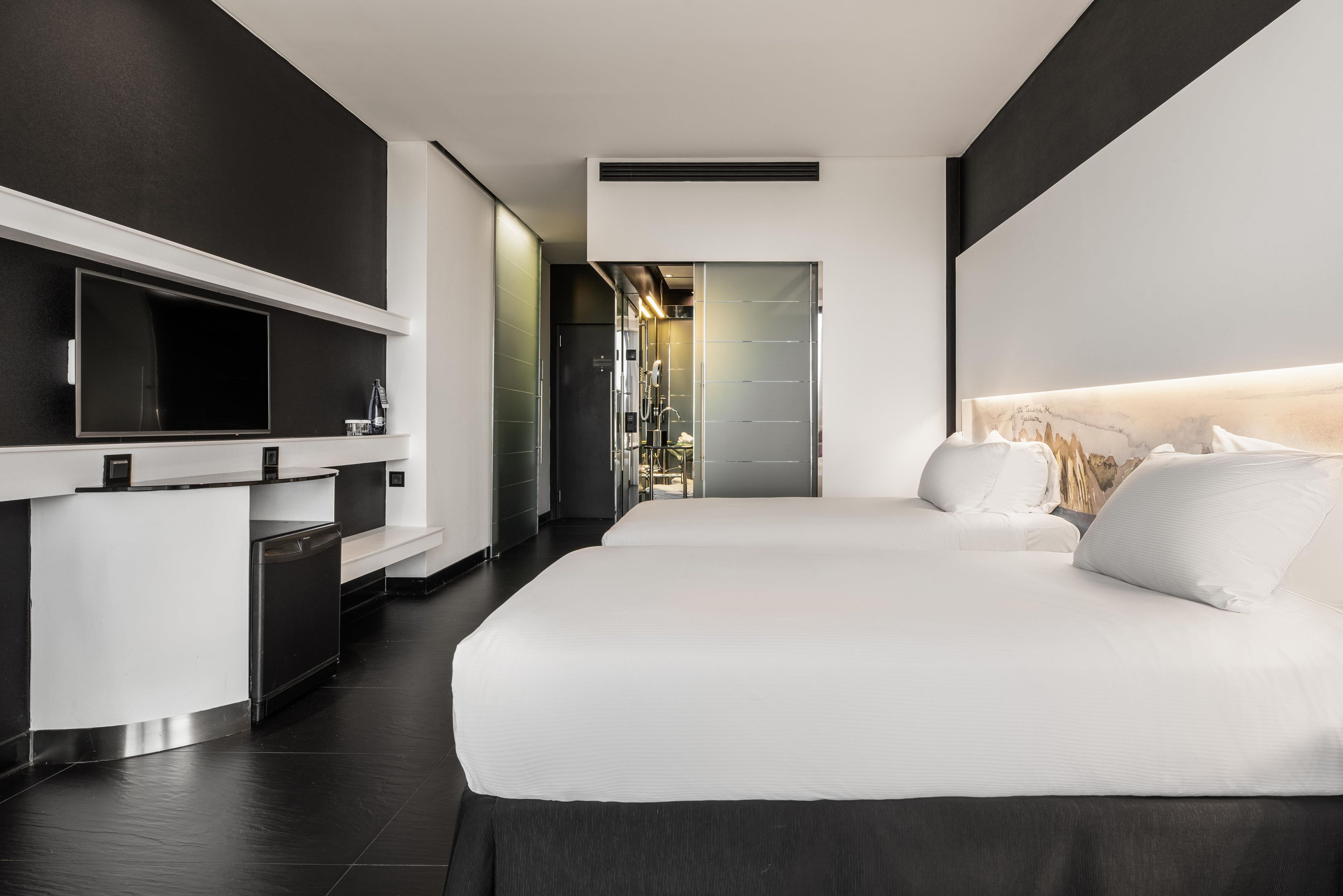 Une chambre d’hôtel moderne avec un grand lit, un petit bureau et un dressing.