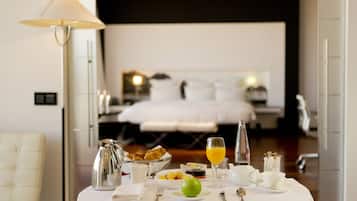 A breakfast table with a pitcher, bowl, fruit, and a glass of orange juice in a hotel room.