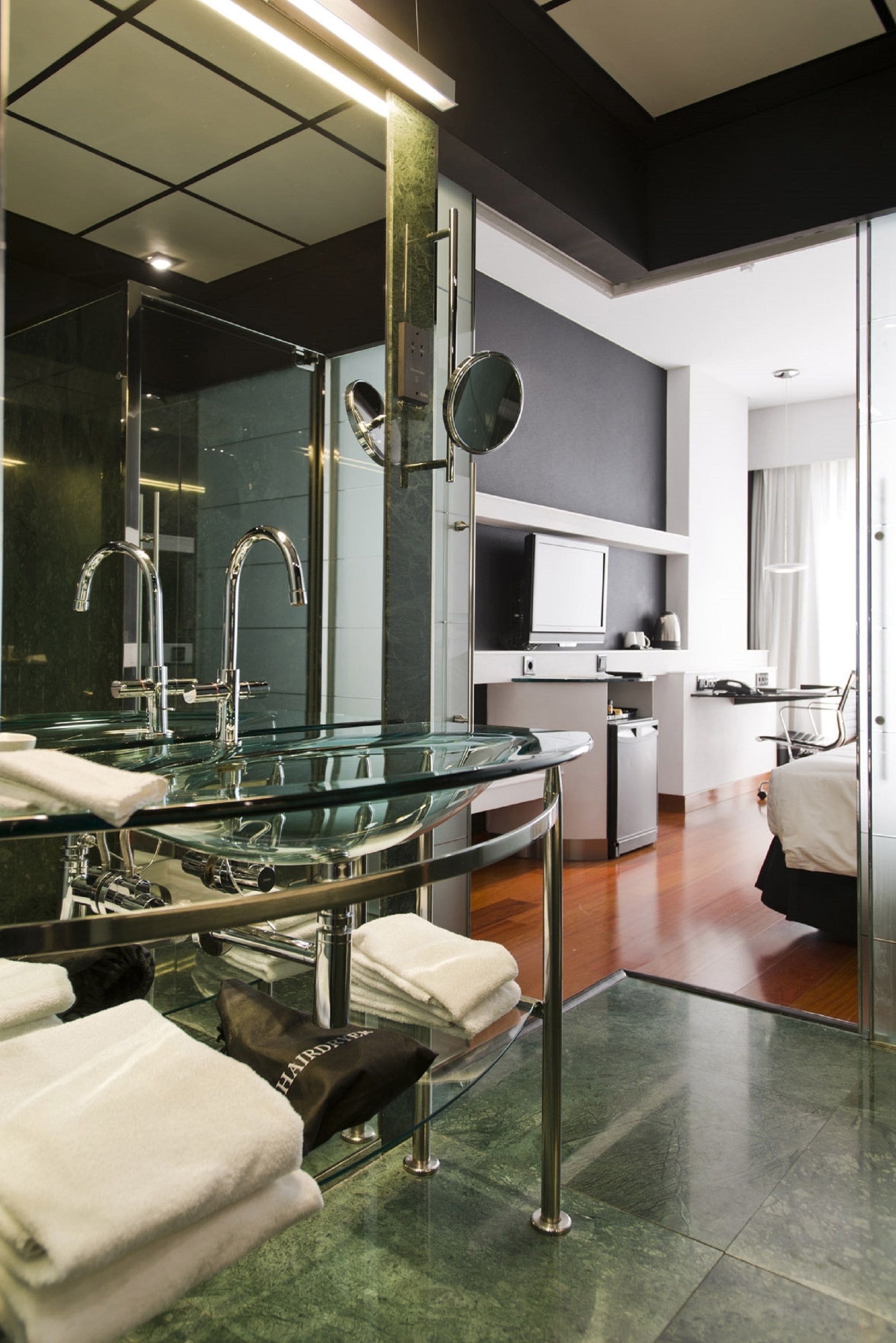 A modern bathroom with a glass sink, chrome fixtures, and a large mirror.