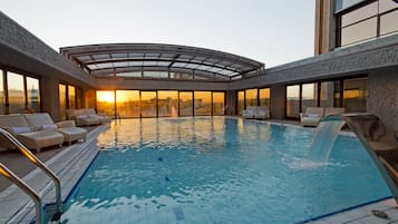 Una piscina cubierta, una piscina al aire libre, tumbonas