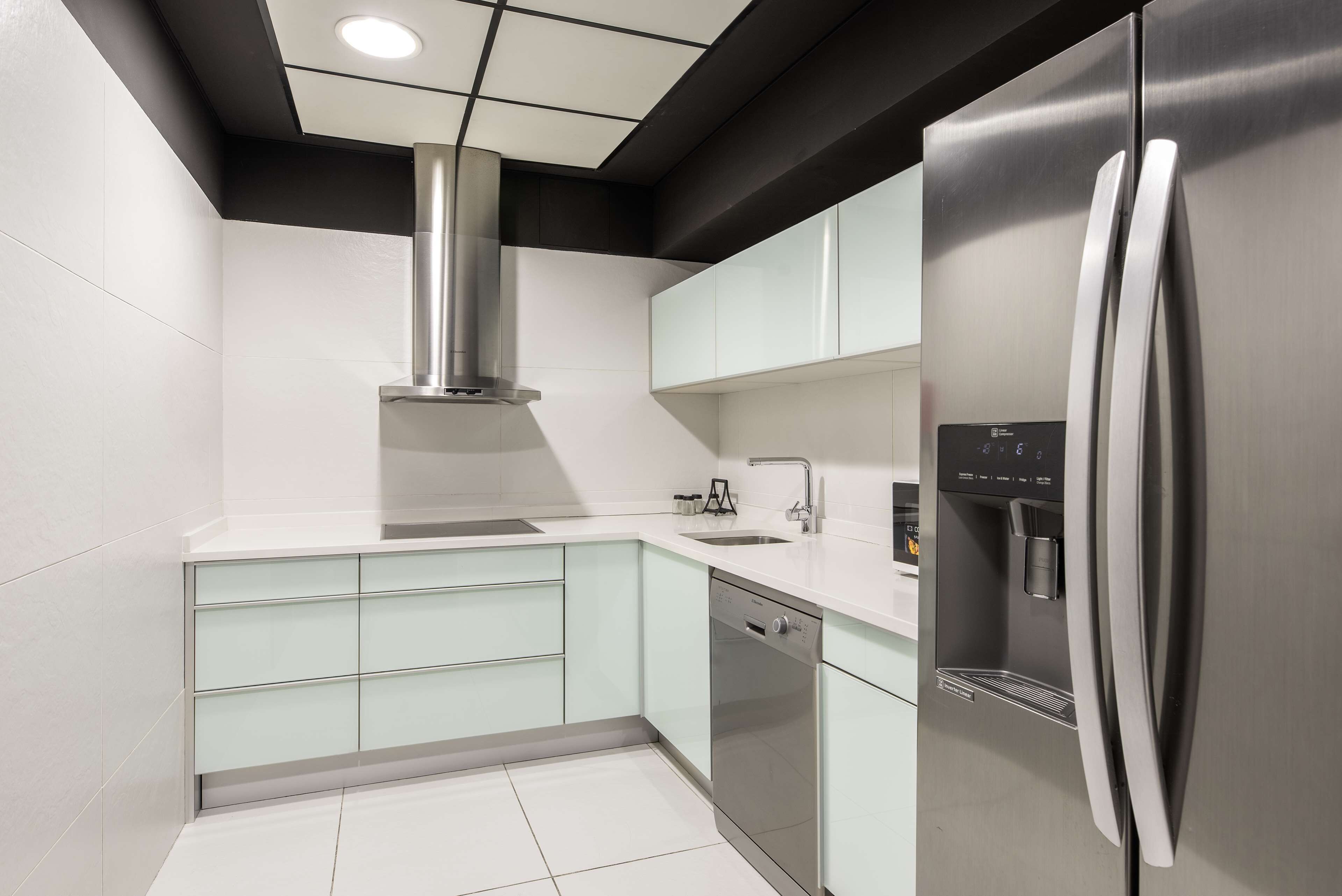 Una cocina moderna con un refrigerador de acero inoxidable, lavavajillas y dispensador de agua.