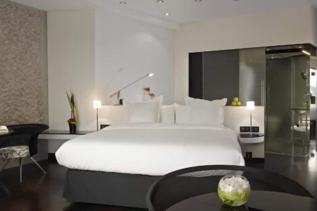 Een moderne hotelkamer met een groot bed, nachtkastjes, een bureau en een stoel.
