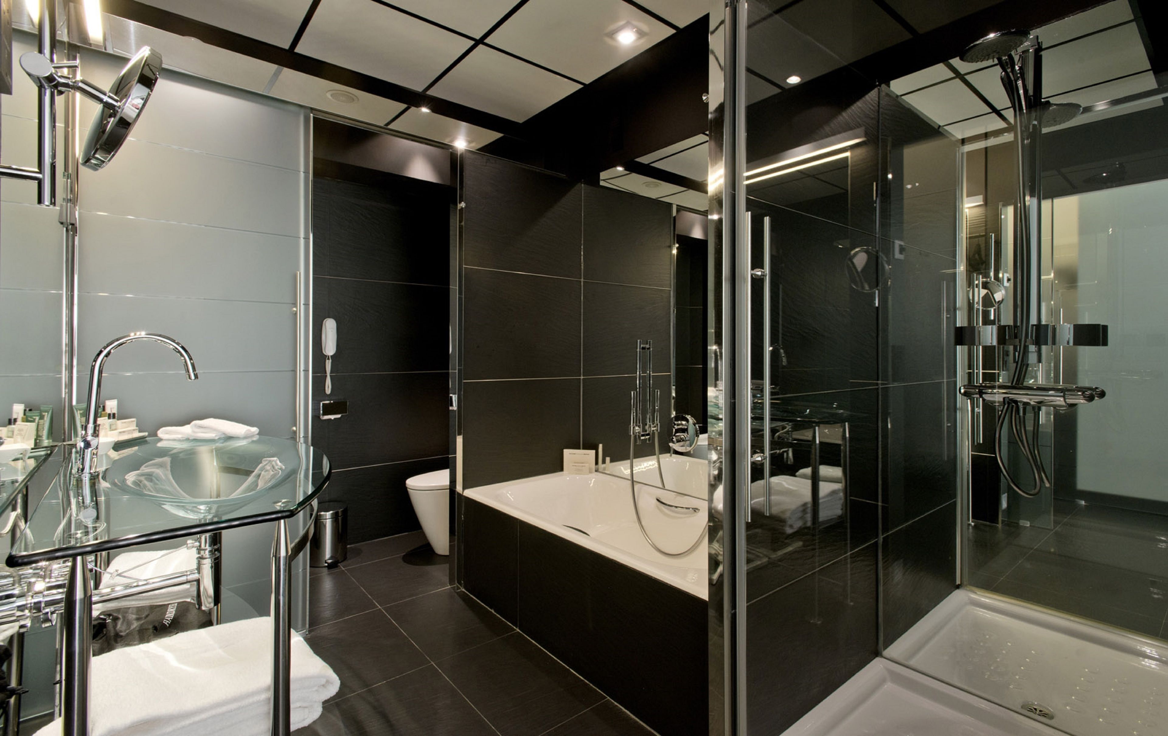A modern bathroom with a glass-enclosed shower, a standalone sink, and a toilet.