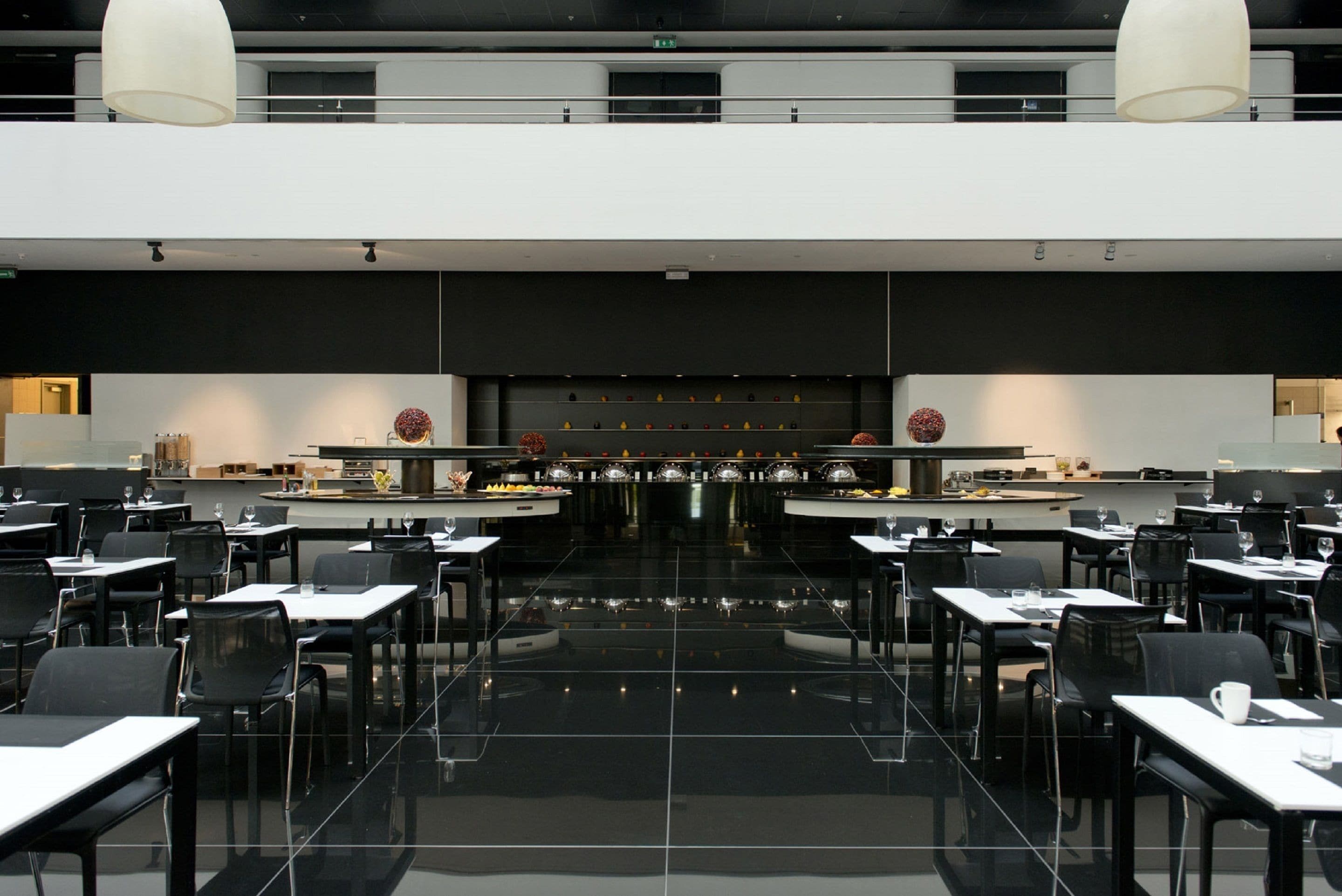 Un restaurant moderne avec un long comptoir, des chaises noires et un sol ciré.