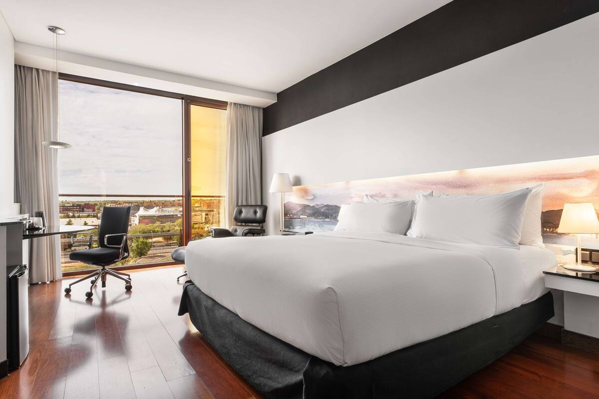 Een moderne hotelkamer met een groot bed, een bureau en een stoel.