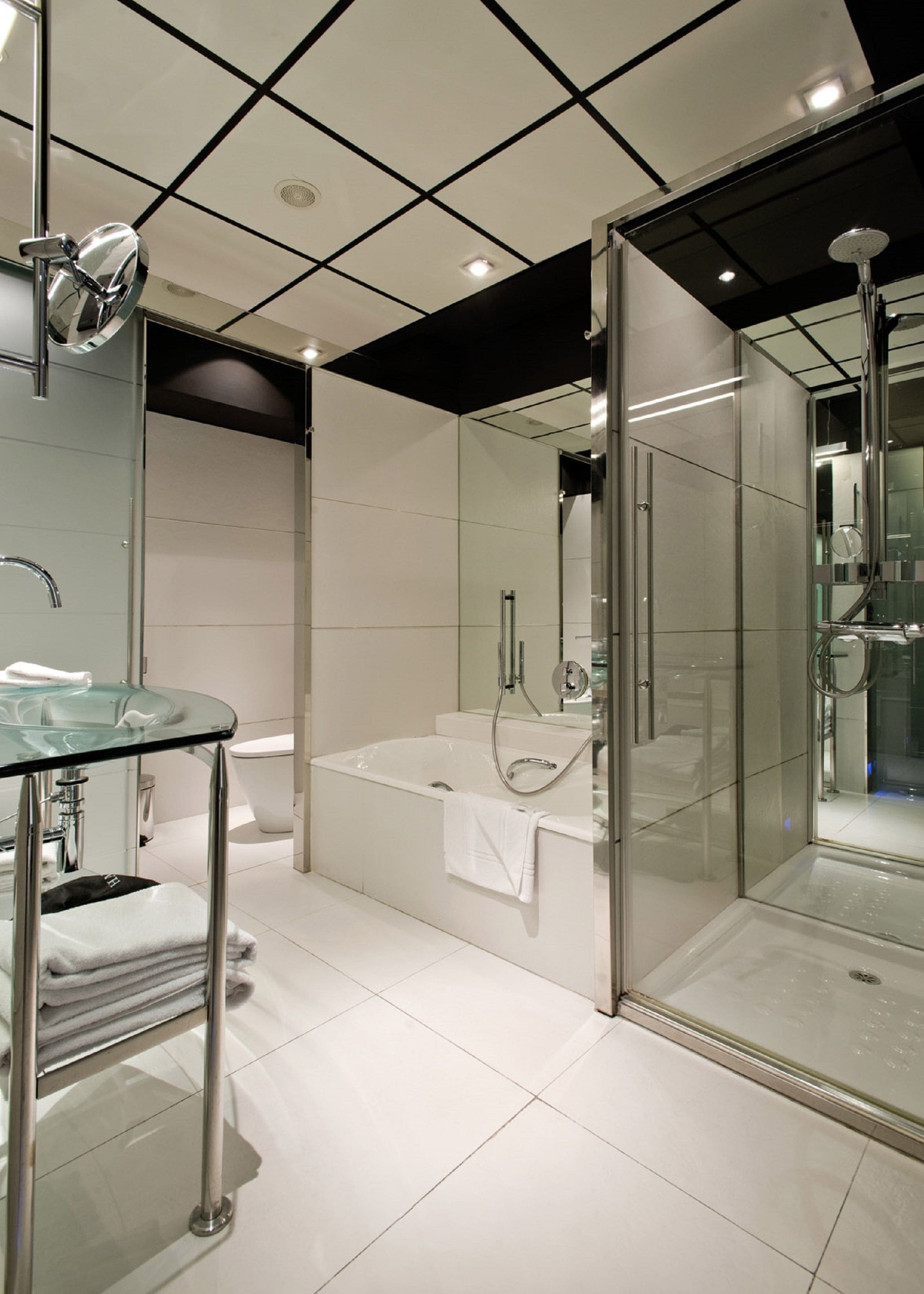 A modern bathroom with a glass-enclosed shower, a glass sink, and a separate bathtub.