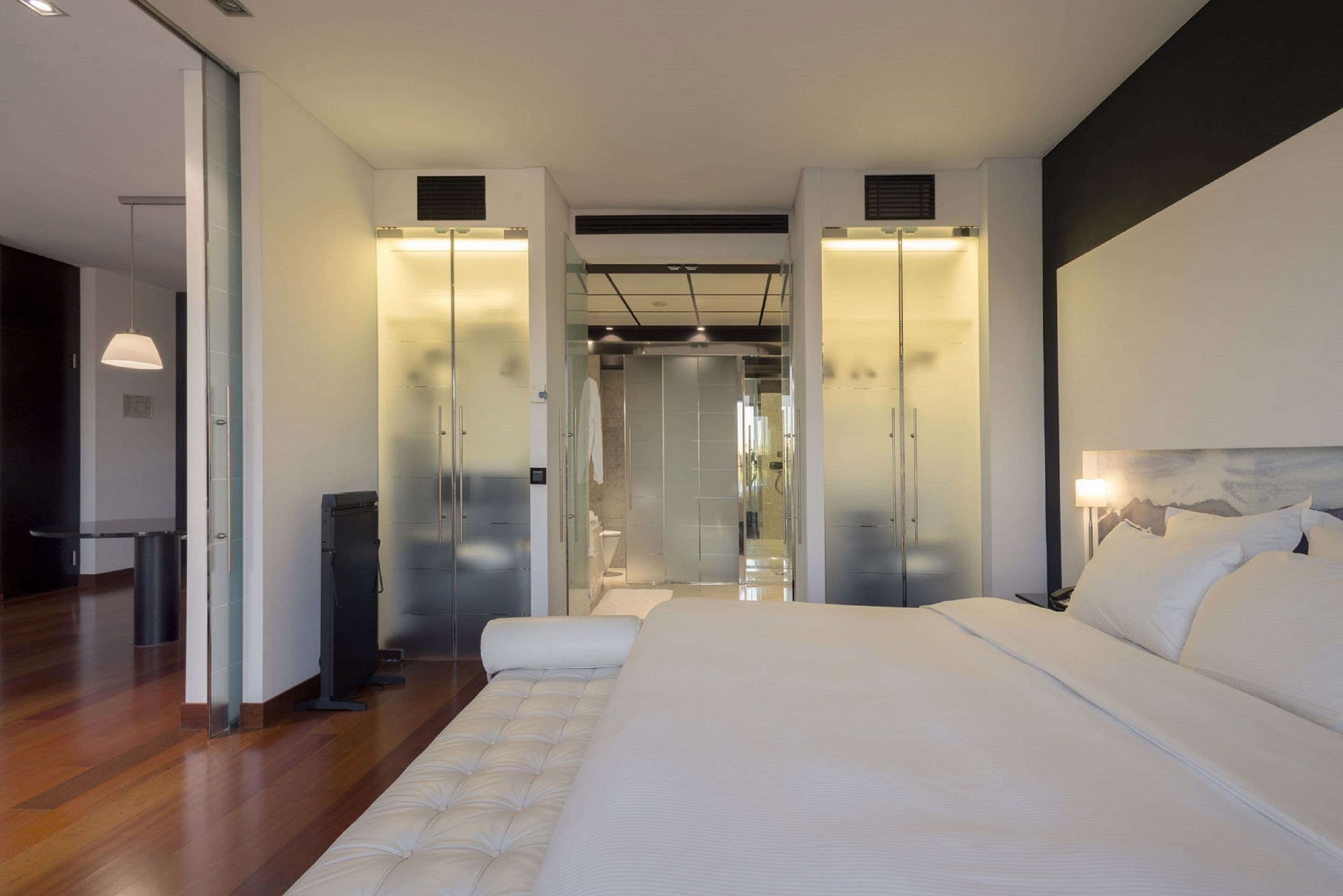 Een moderne hotelkamer met een groot bed, een bureau en een glazen scheidingswand.