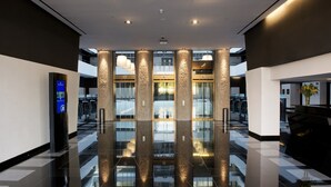 Un hall d’entrée moderne avec une entrée en verre, un sol réfléchissant et un kiosque d’information numérique.