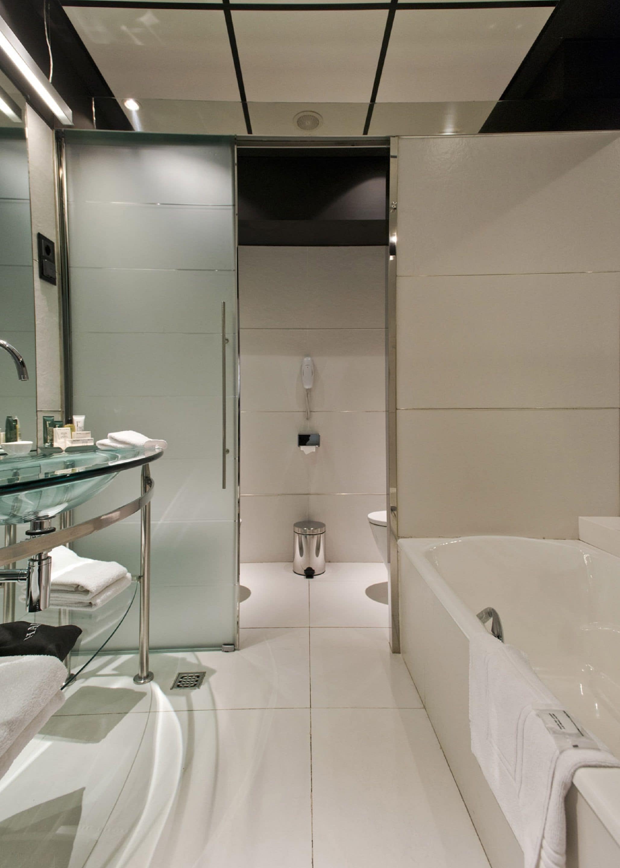 A modern bathroom with a glass shower enclosure, a separate toilet, and a standalone bathtub.