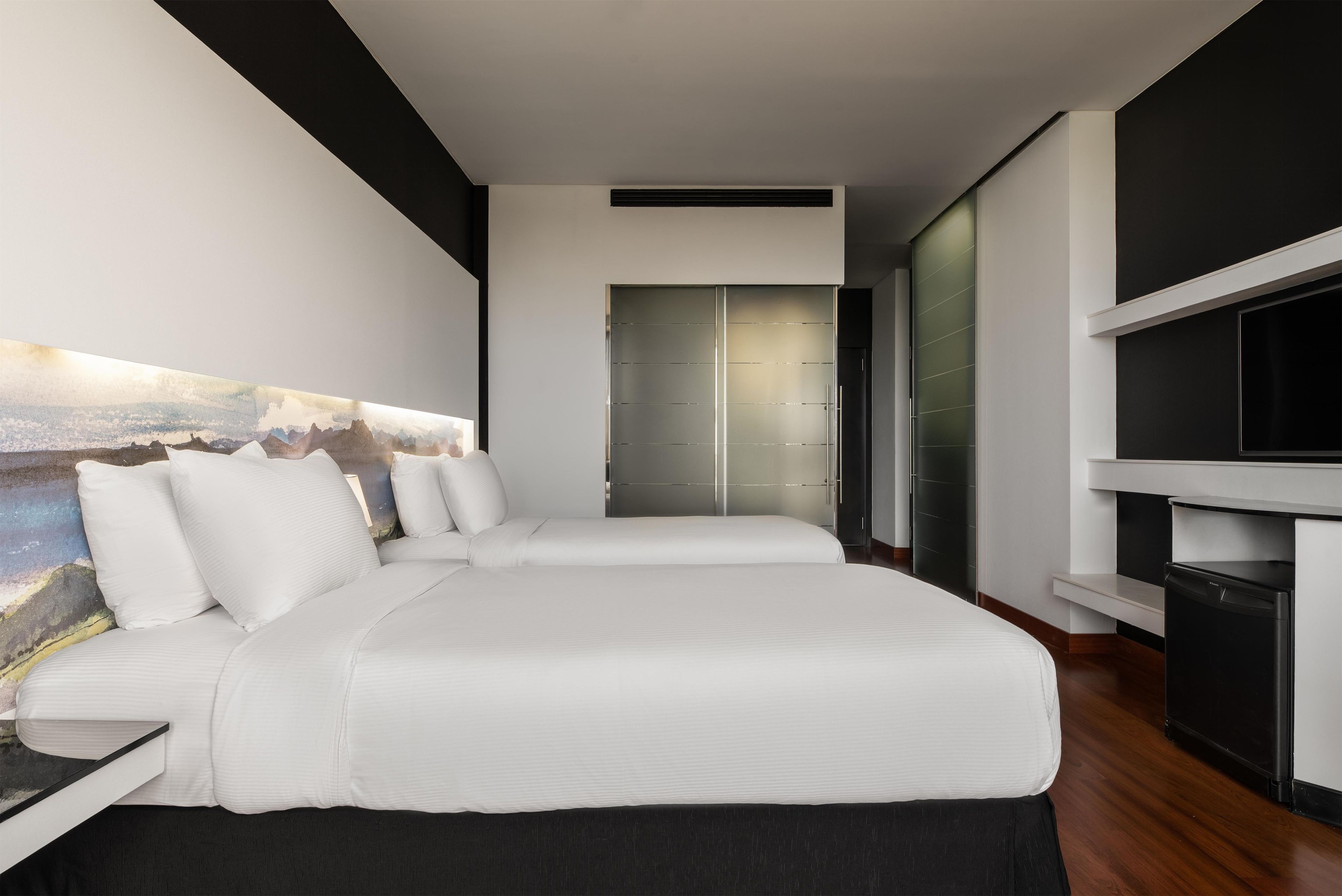 Una camera d'albergo moderna con un letto grande, una TV a schermo piatto e un quadro appeso al muro.