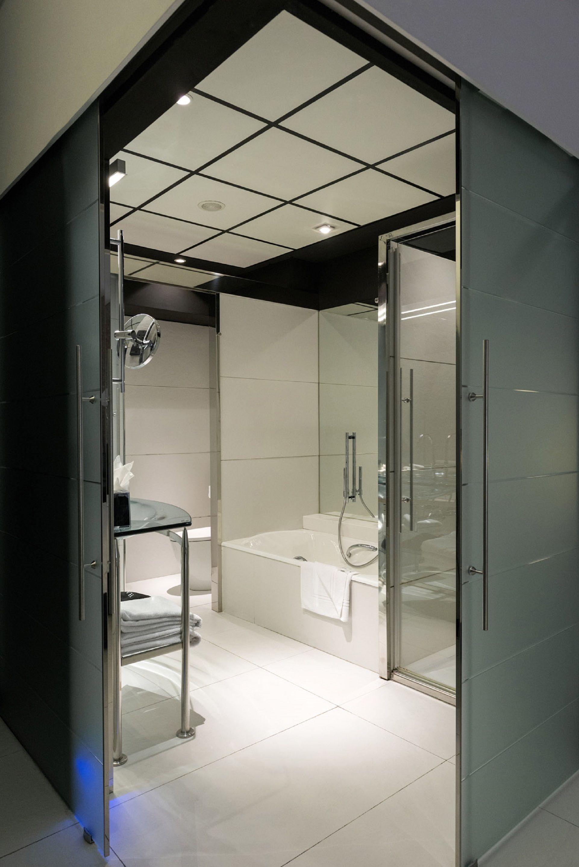 A modern bathroom with a glass shower enclosure, a glass-enclosed vanity, and a white bathtub.