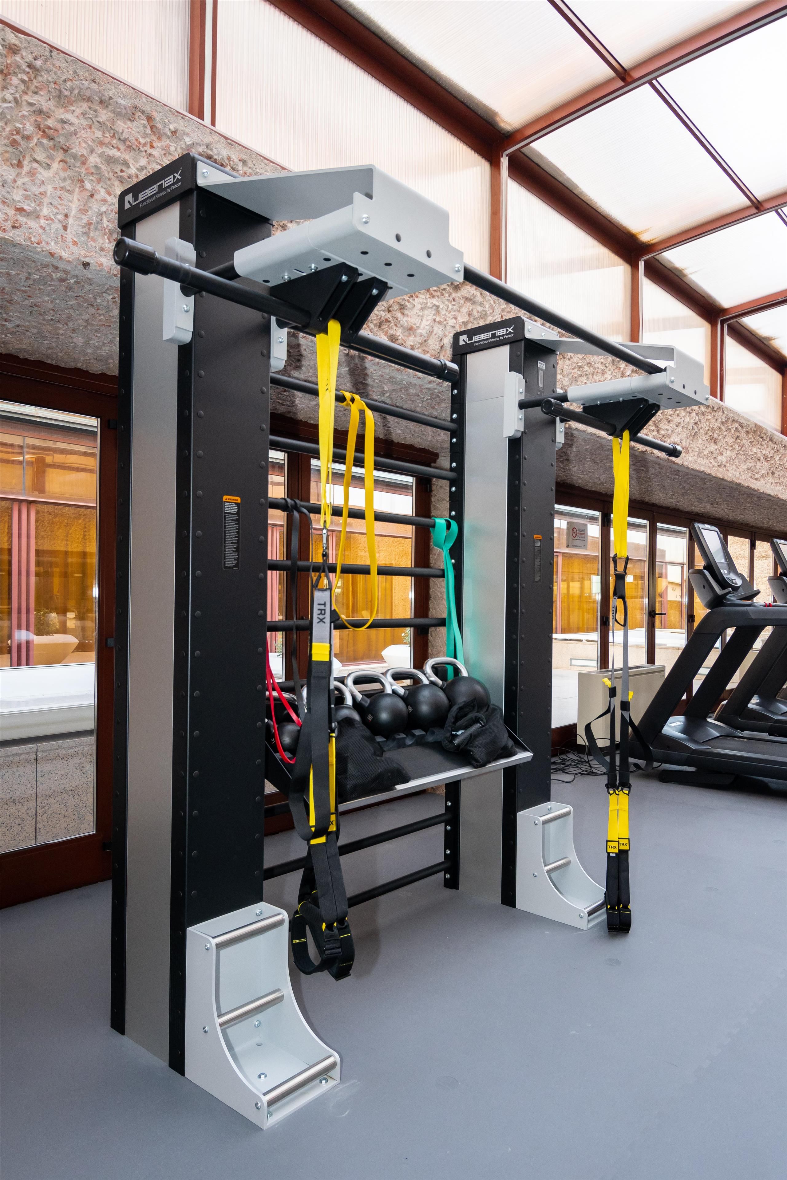 Ein Fitnessraum mit TRX-Aufhängungsgurten, einer Klimmzugstange und einem Laufband.