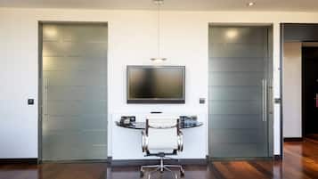 Ein moderner Büroraum mit einem großen Flachbildfernseher an der Wand, einem weißen Bürostuhl und einem Schreibtisch mit einem Computer.