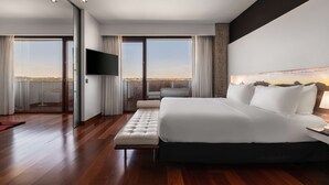 Une chambre d’hôtel moderne dotée d’un grand lit, d’une télévision à écran plat et d’un balcon offrant une vue sur la ville.